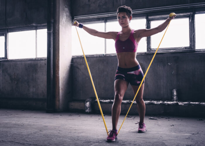 Girl using a resistance band in her exercise routine Full length shot of a sporty girl using a resistance band in her gym exercise routine